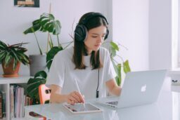 Photo of girl with a laptop and headphones participating in e-learning